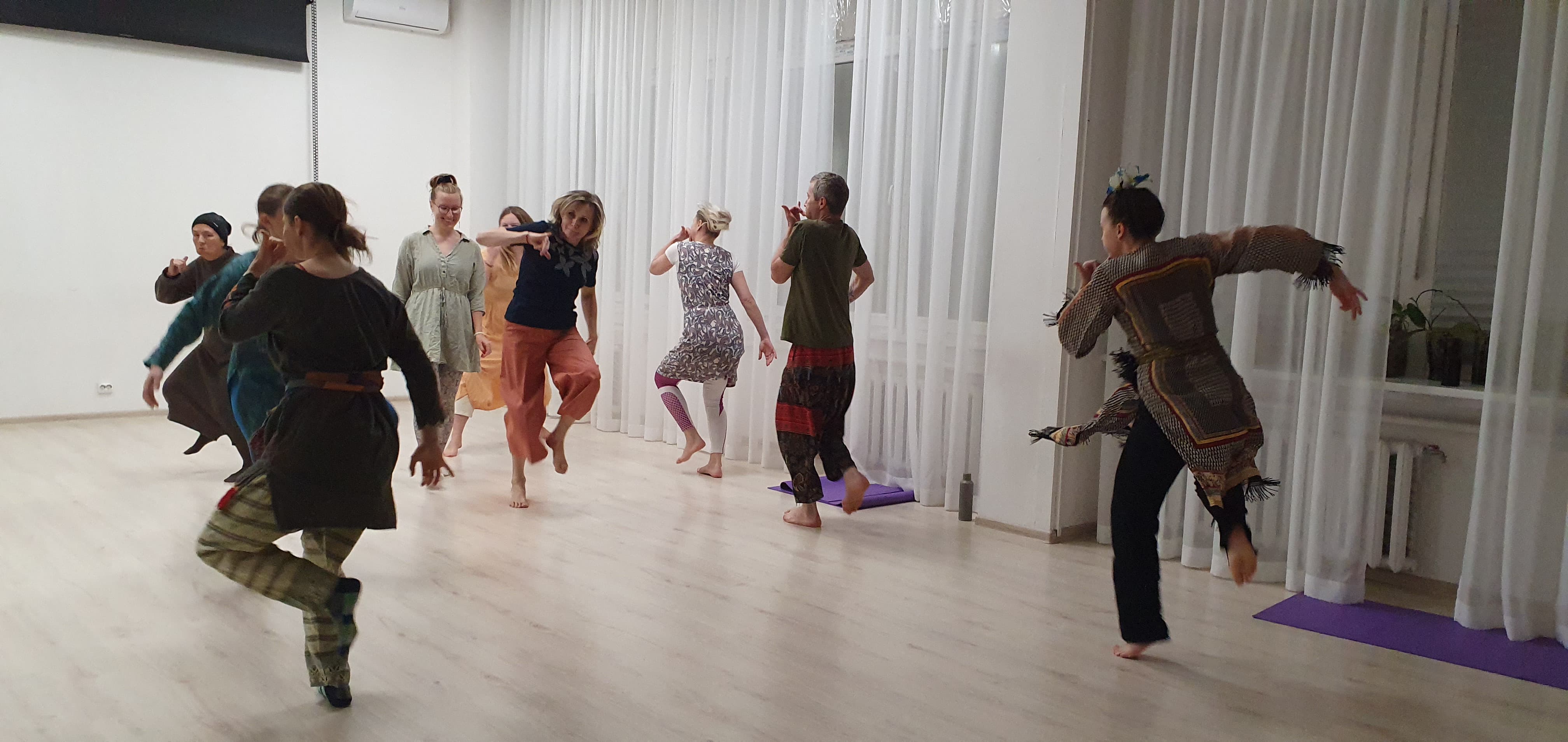 Workshop participants practicing Bharatanatyam movement in a studio
